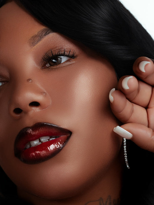 close-up of a woman wearing magnetic lashes with glossy dark red lipstick and long black hair