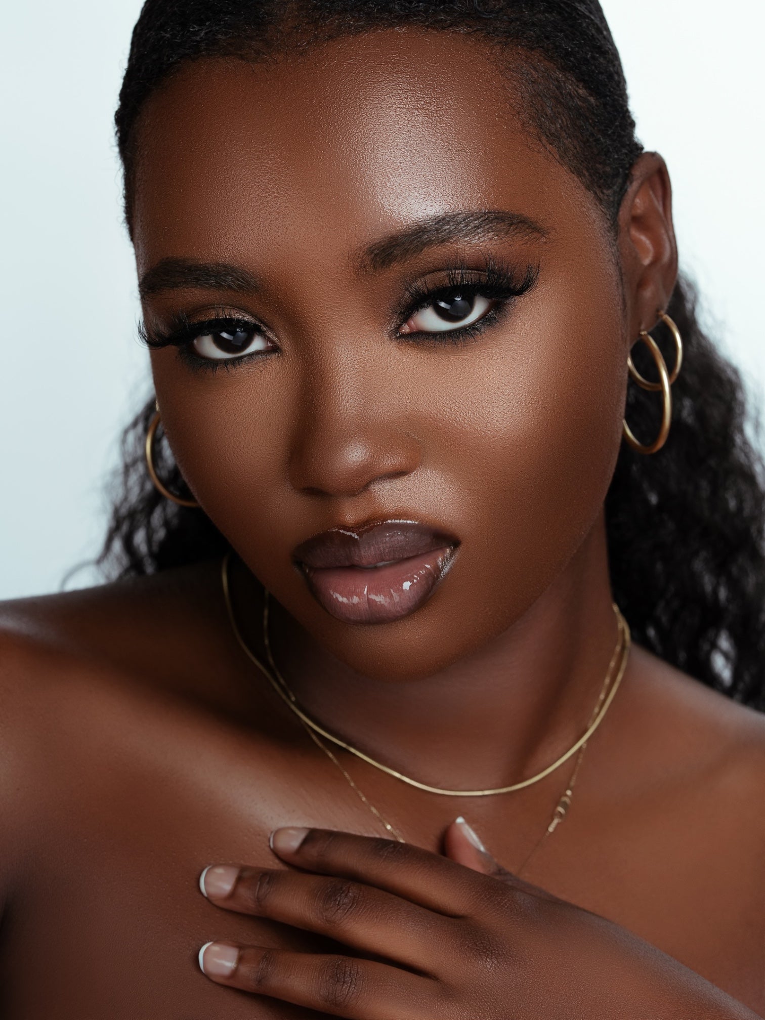 Elegant close-up of a woman wearing luxurious Lucy Lash Box real mink eyelashes with gold hoop earrings and delicate gold necklace