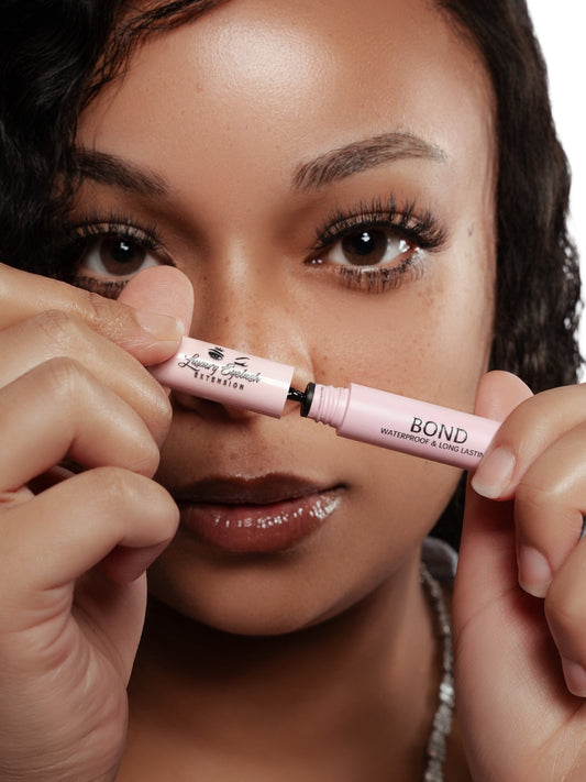 Close-up of a woman holding and opening Seal and Bond Glue for cluster lashes with a pink waterproof and long-lasting adhesive tube